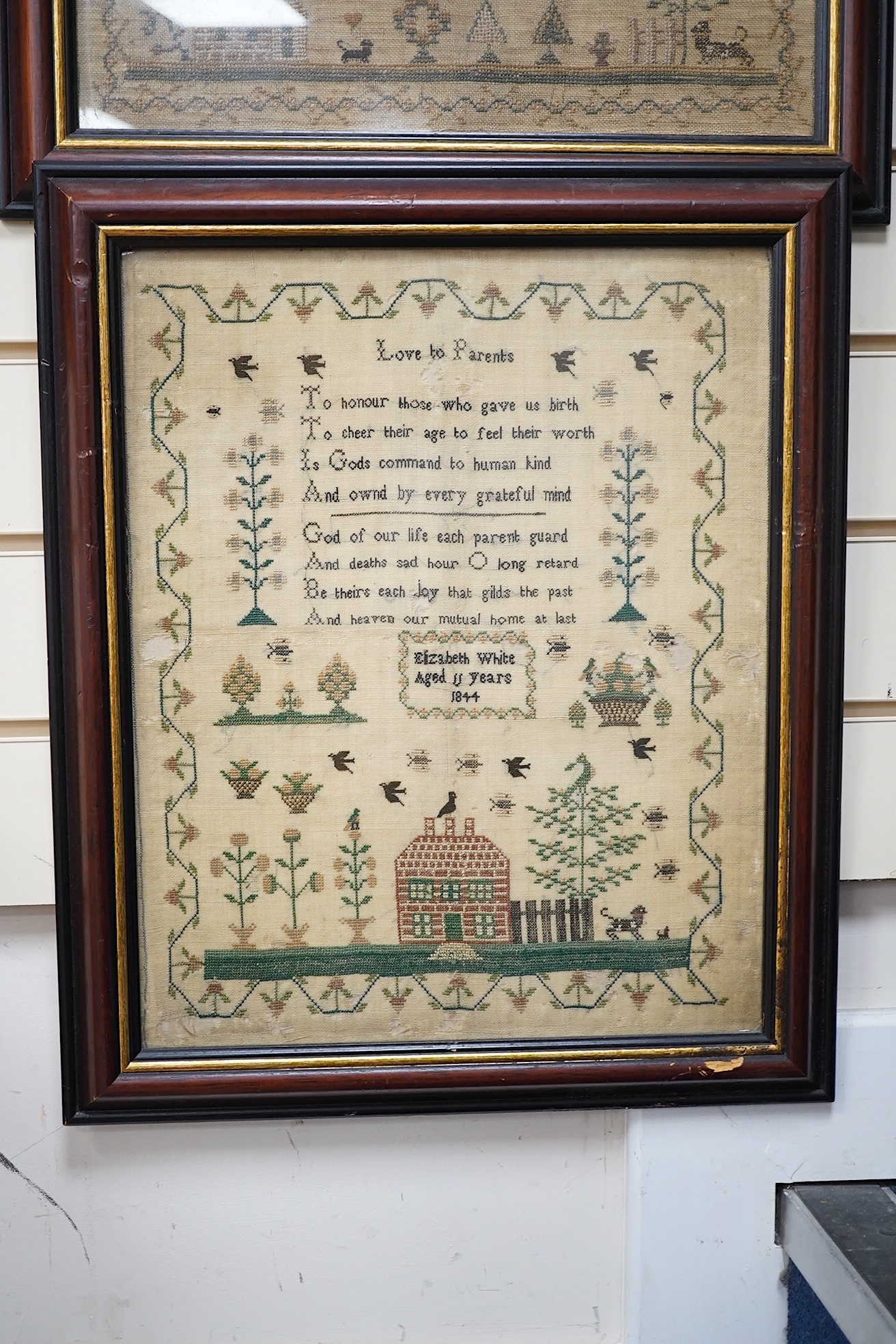 Two mid 19th century samplers worked by Elizabeth White, one dated 1842 aged 8 years, the other 1844 aged 11 years, both worked with a country scene of a house, birds, dogs and trees, the earlier sampler with a top panel